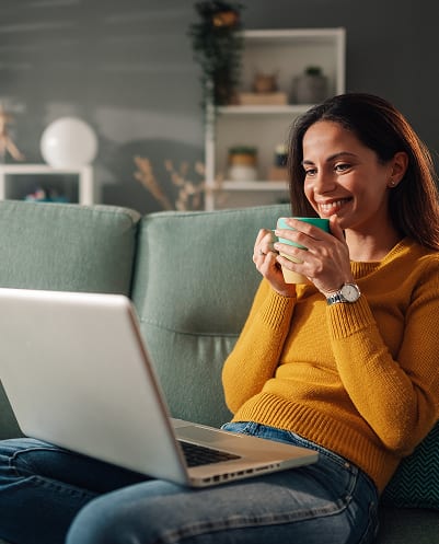 Resident relaxing on a sofa with a laptop in a cable- and high-speed-internet-ready Morse Creek apartment