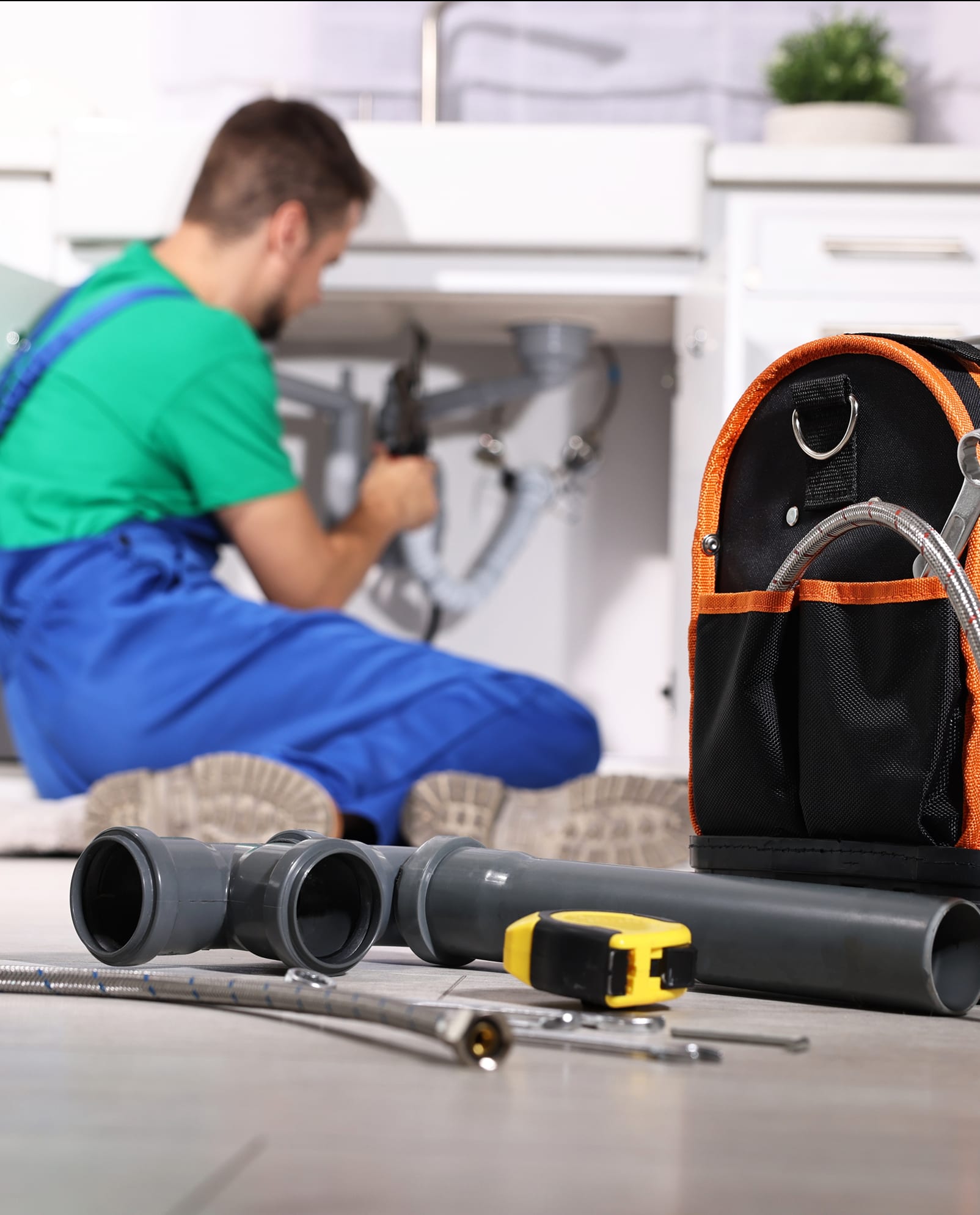 On-site maintenance technician repairing plumbing under a kitchen sink at Morse Creek Apartments