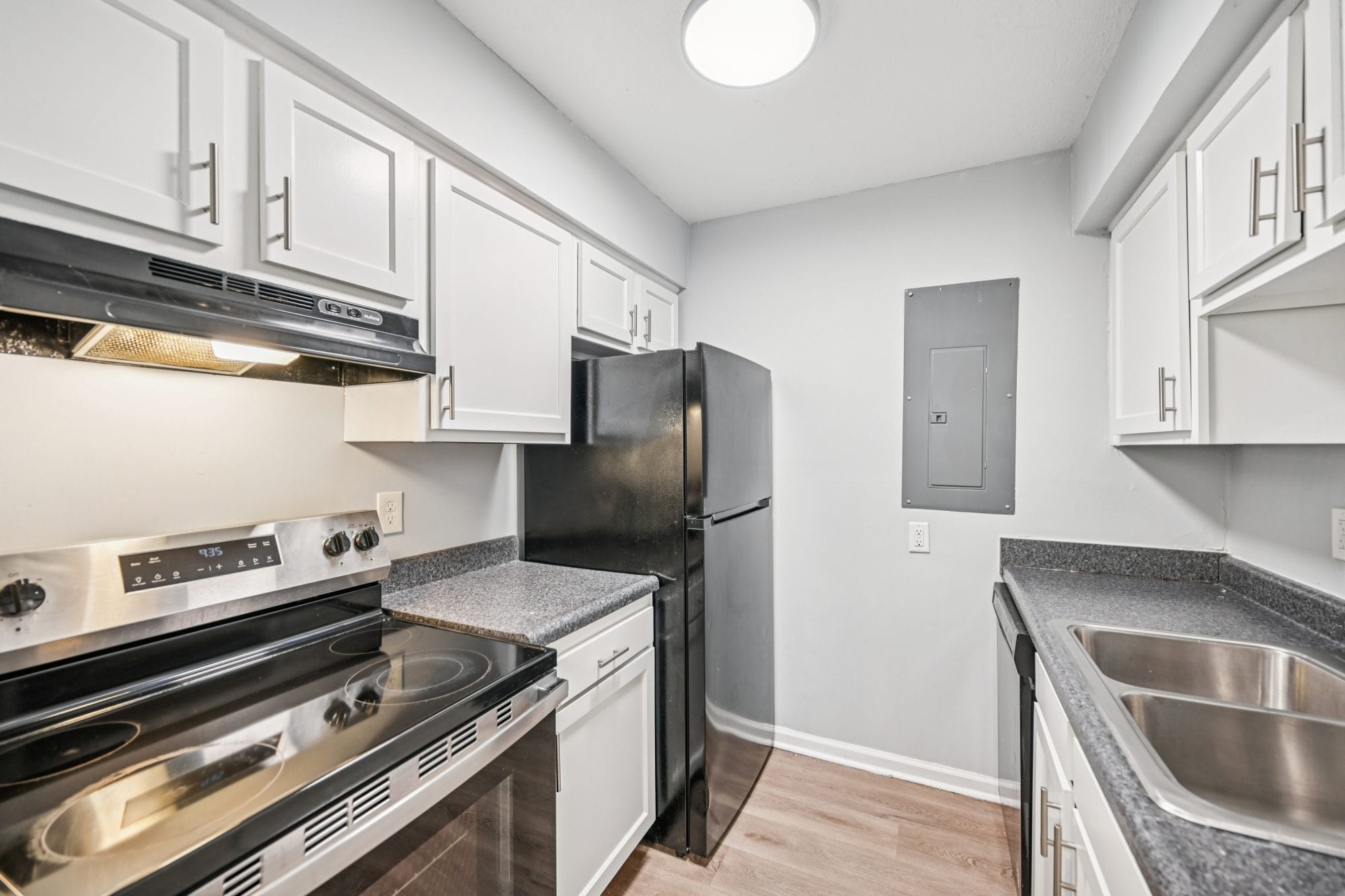 Renovated apartment kitchen with stainless steel range, refrigerator, and white cabinets at Morse Creek Apartments