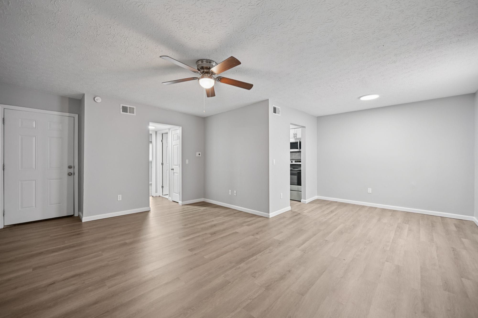 Bright, open living room with ceiling fan and wood-look flooring in a newly renovated Morse Creek apartment